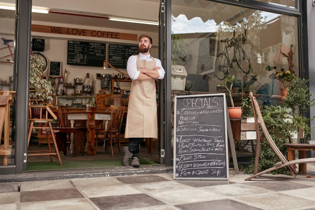 man standing in front of his restaurant